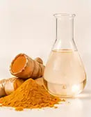 A glass flask of golden extract beside turmeric root