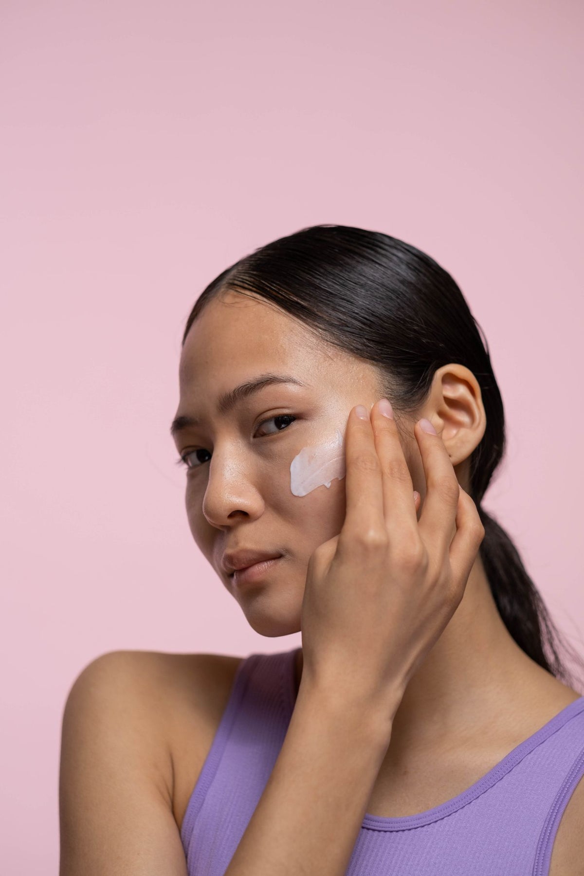 A woman smoothing cream onto her cheek